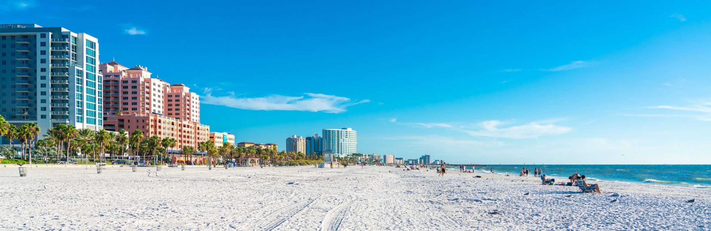 Clearwater beach with hotels, white sand, blue ocean, and people being monitored by commercial surveillance camera systems