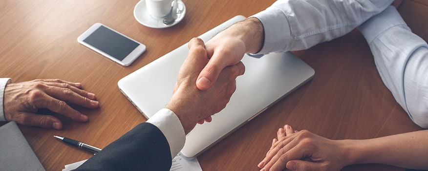 Two business professionals shaking hands while sitting at a table discussing security system companies in Tampa